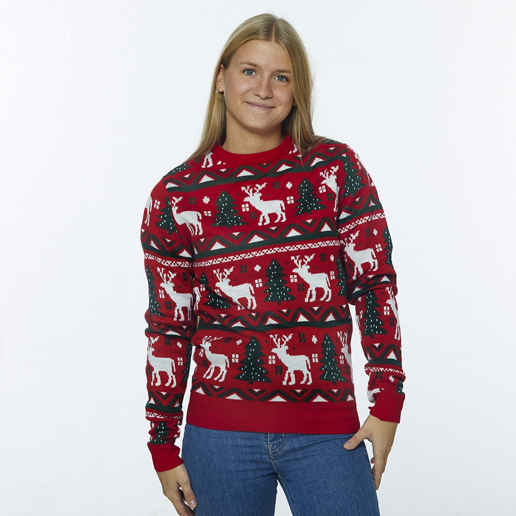 Een vrouw die een rode kersttrui draagt met rendieren en kerstbomen.