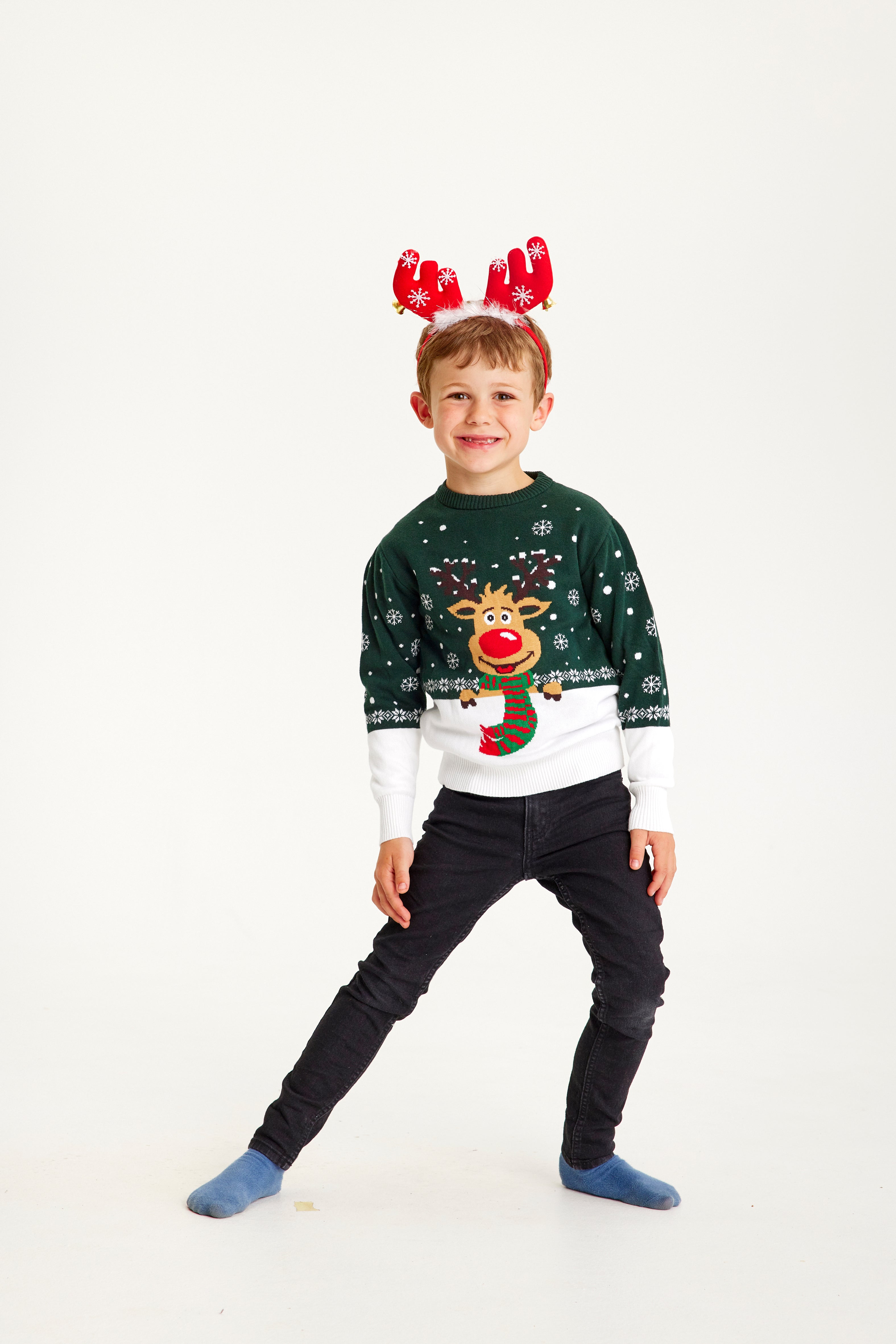 Et barn iført en grøn julesweater med Rudolf på.