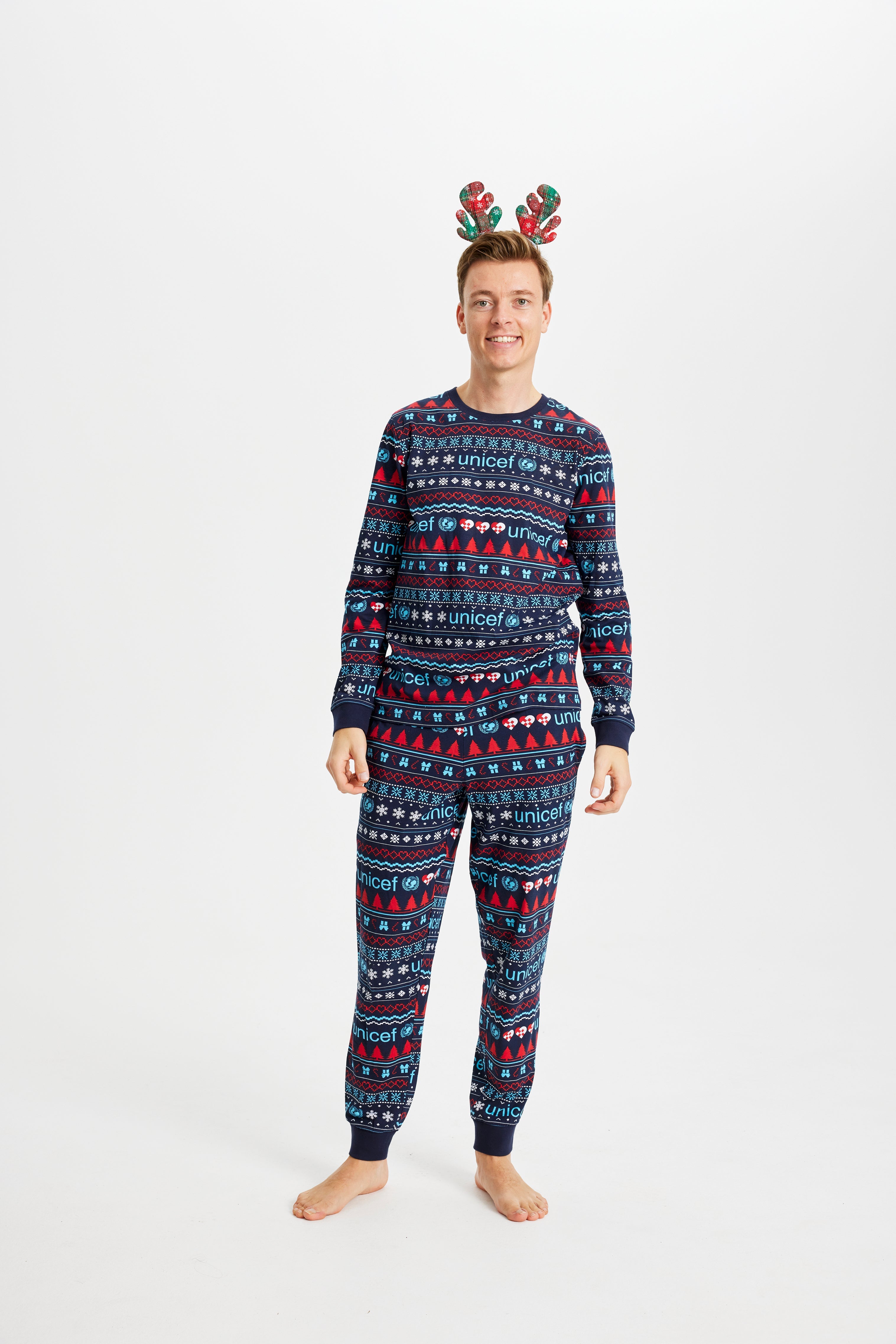 En mand poserer i sine julepyjamas med julemønster på.
