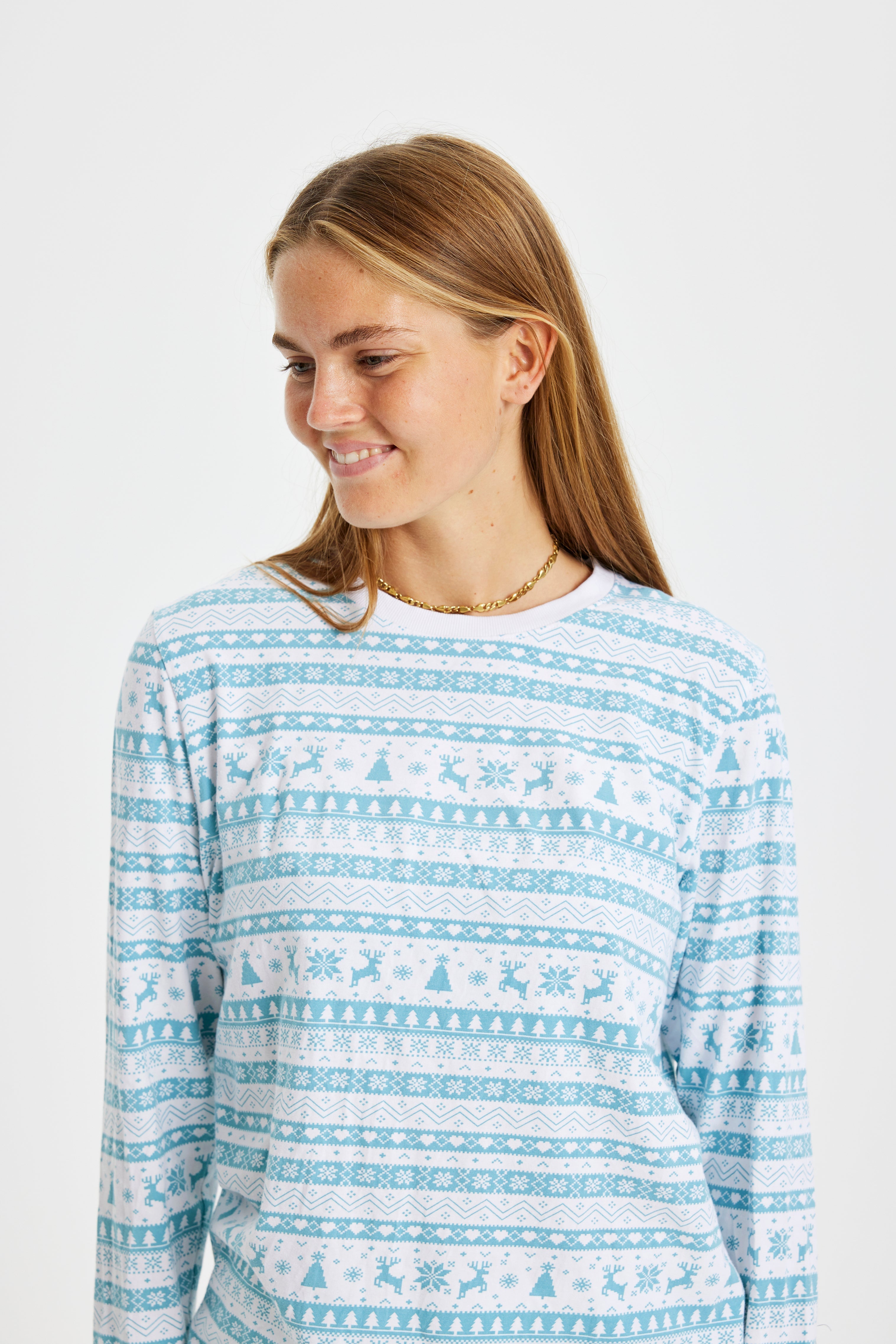 Een vrouw die opzij kijkt en een lichtblauwe kerstpyjama draagt.