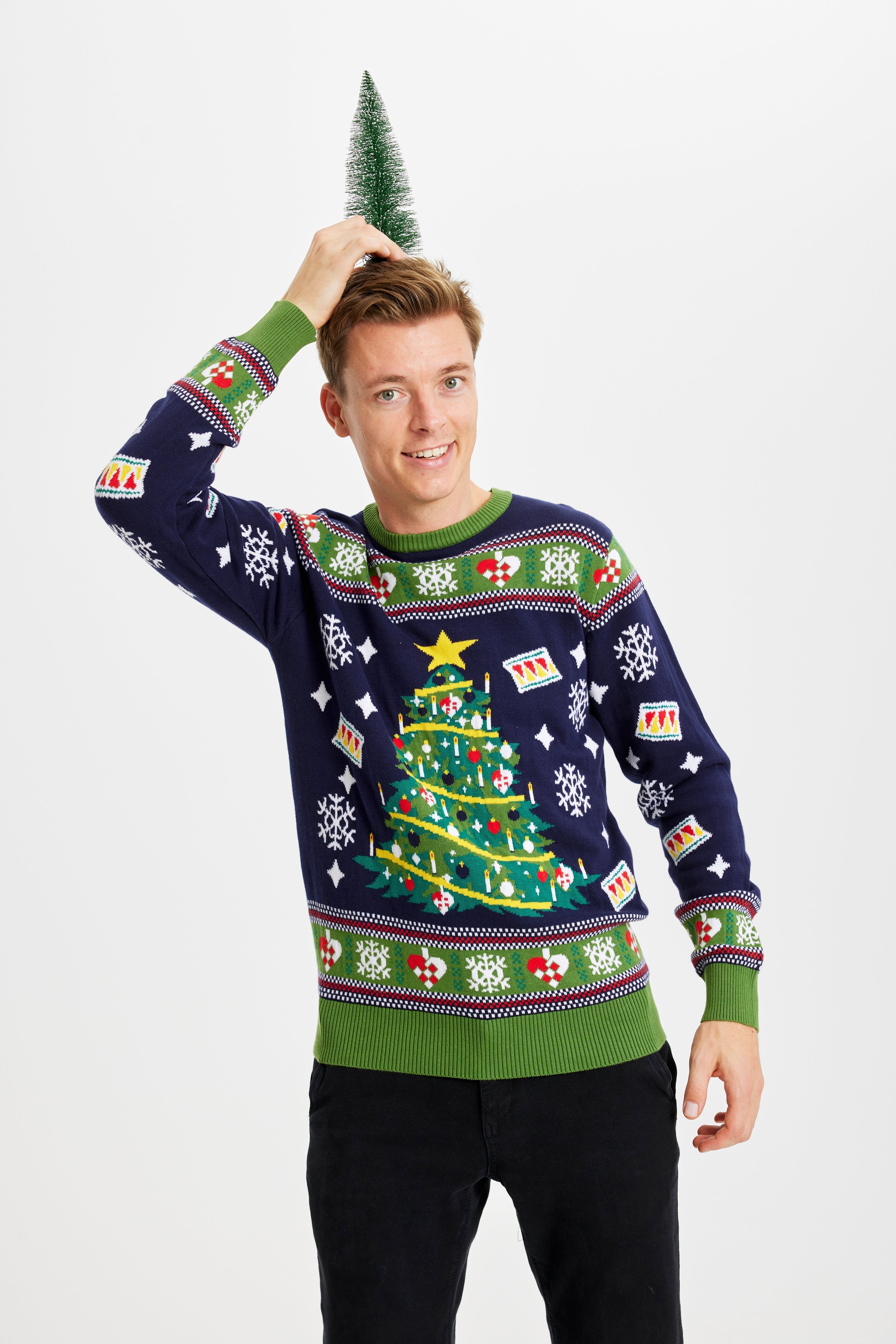 Een man poseert in een blauwgroene outfit met een knipperende kerstboom.