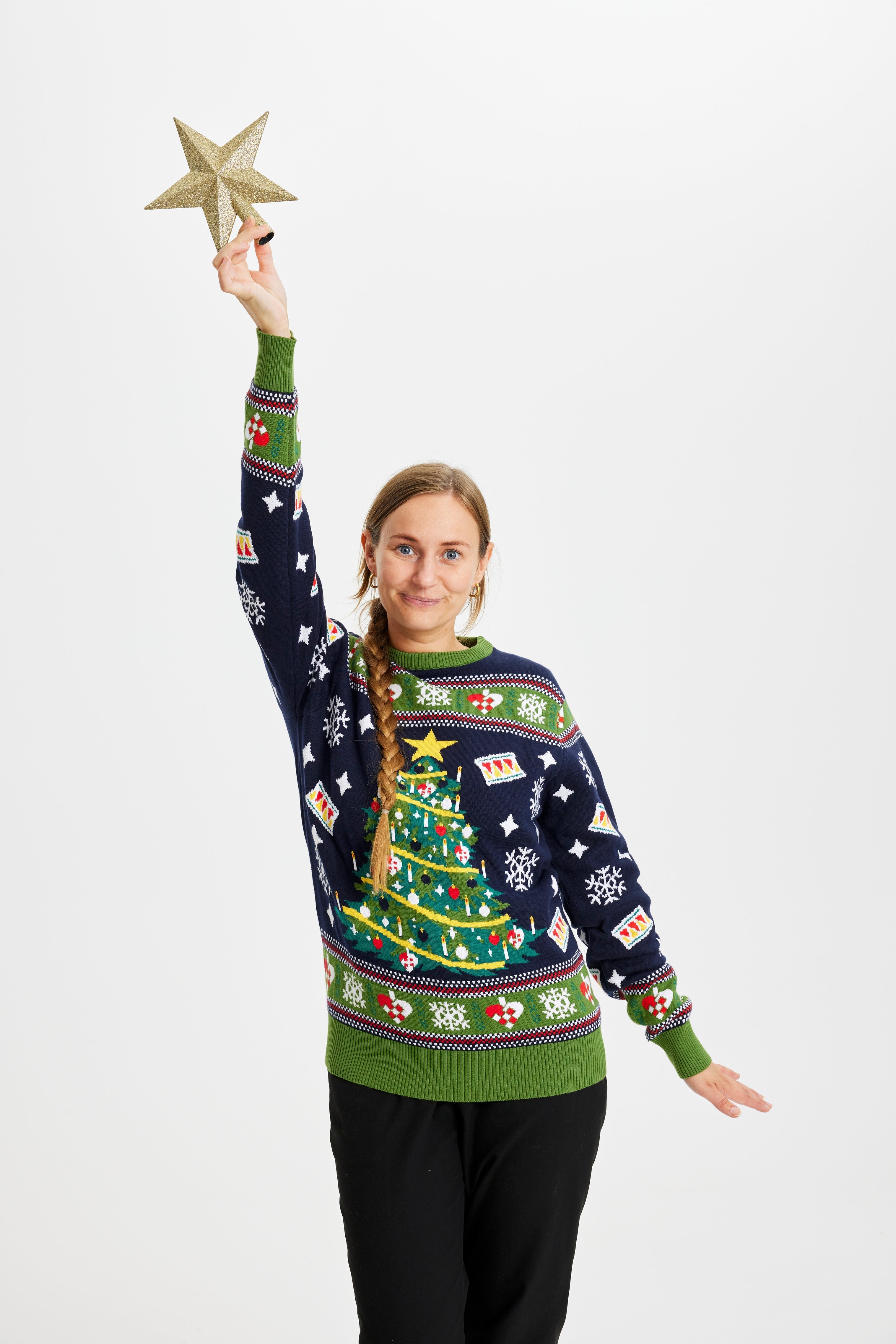 Een poserende vrouw in een blauwgroene outfit met een knipperende kerstboom.