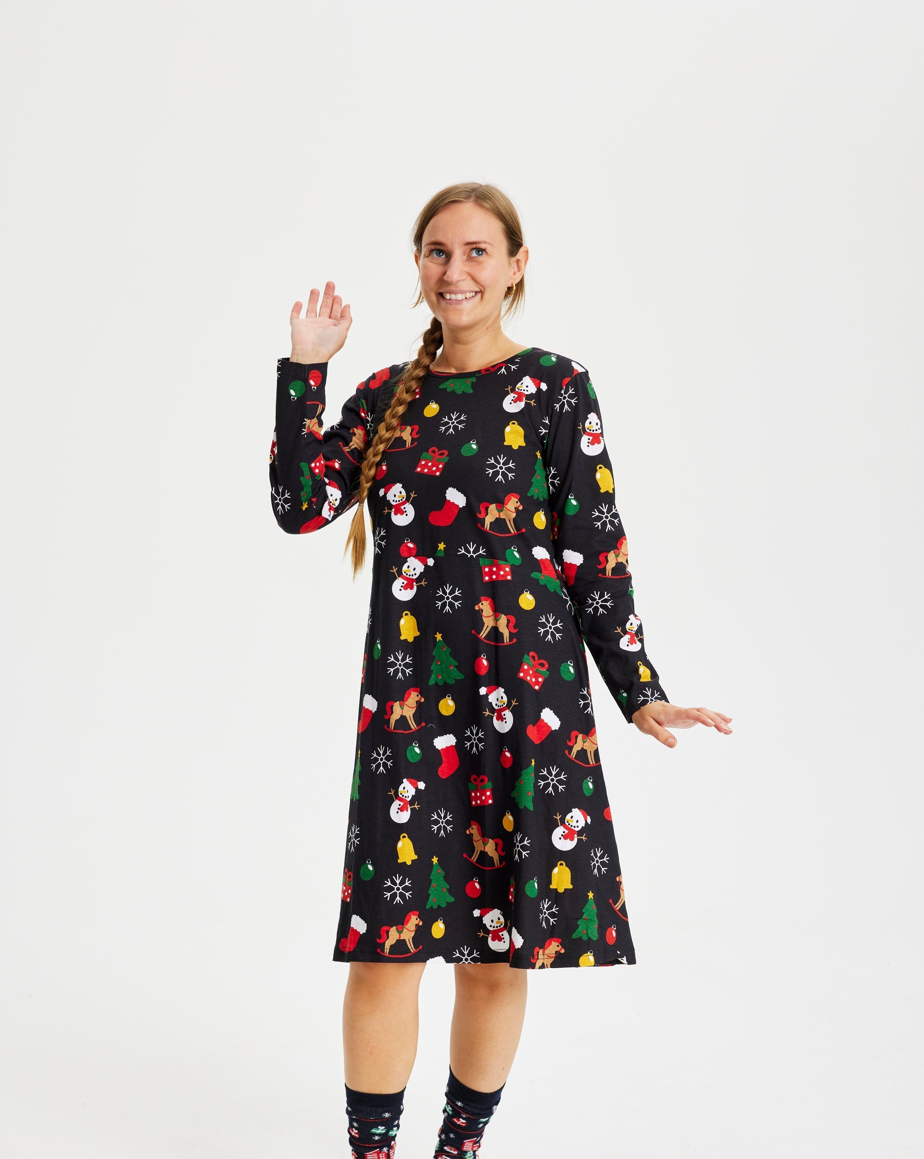 En kvinde står og vinker og er iført en sort julekjole.