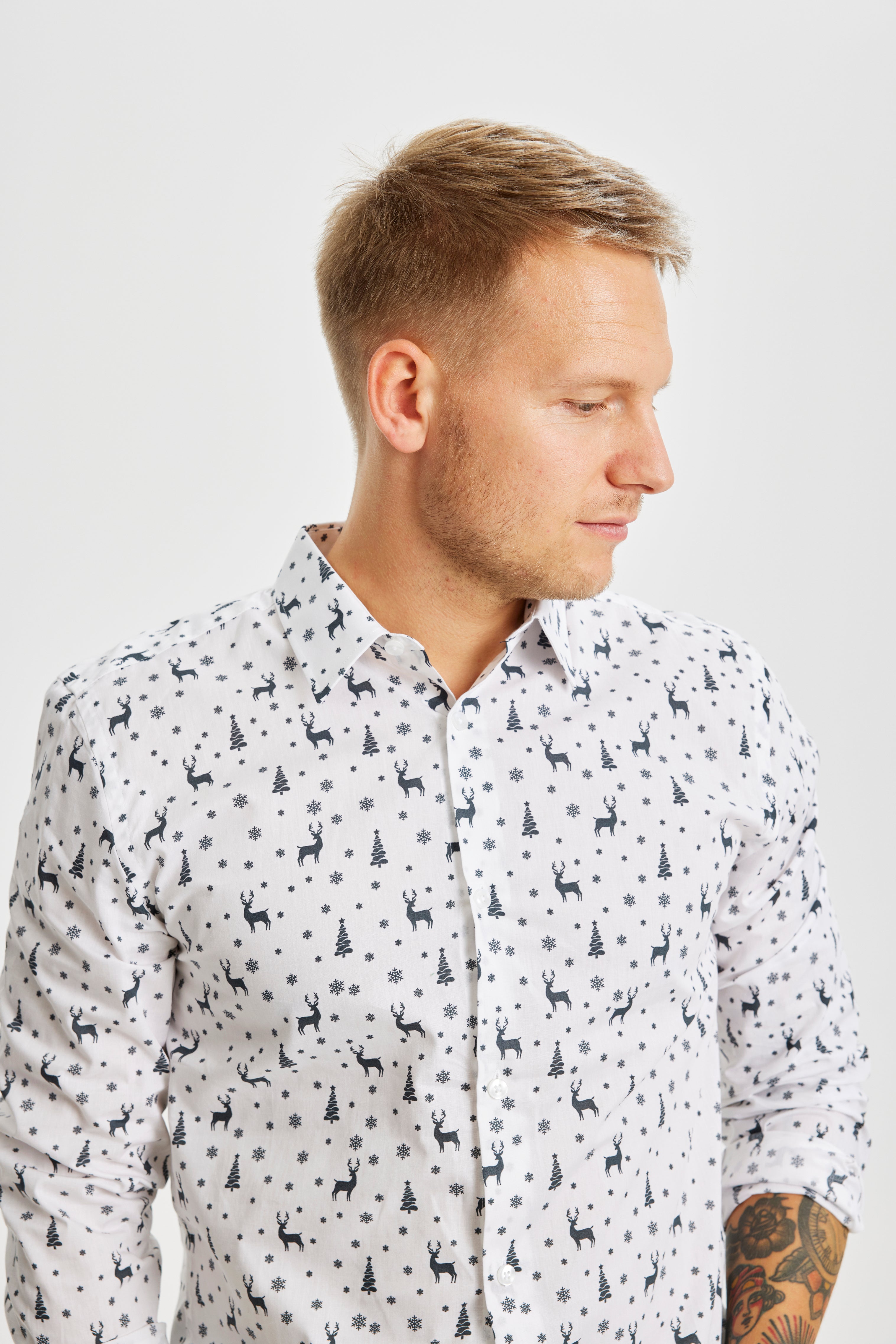 Een man die opzij kijkt en een wit kerstoverhemd draagt.