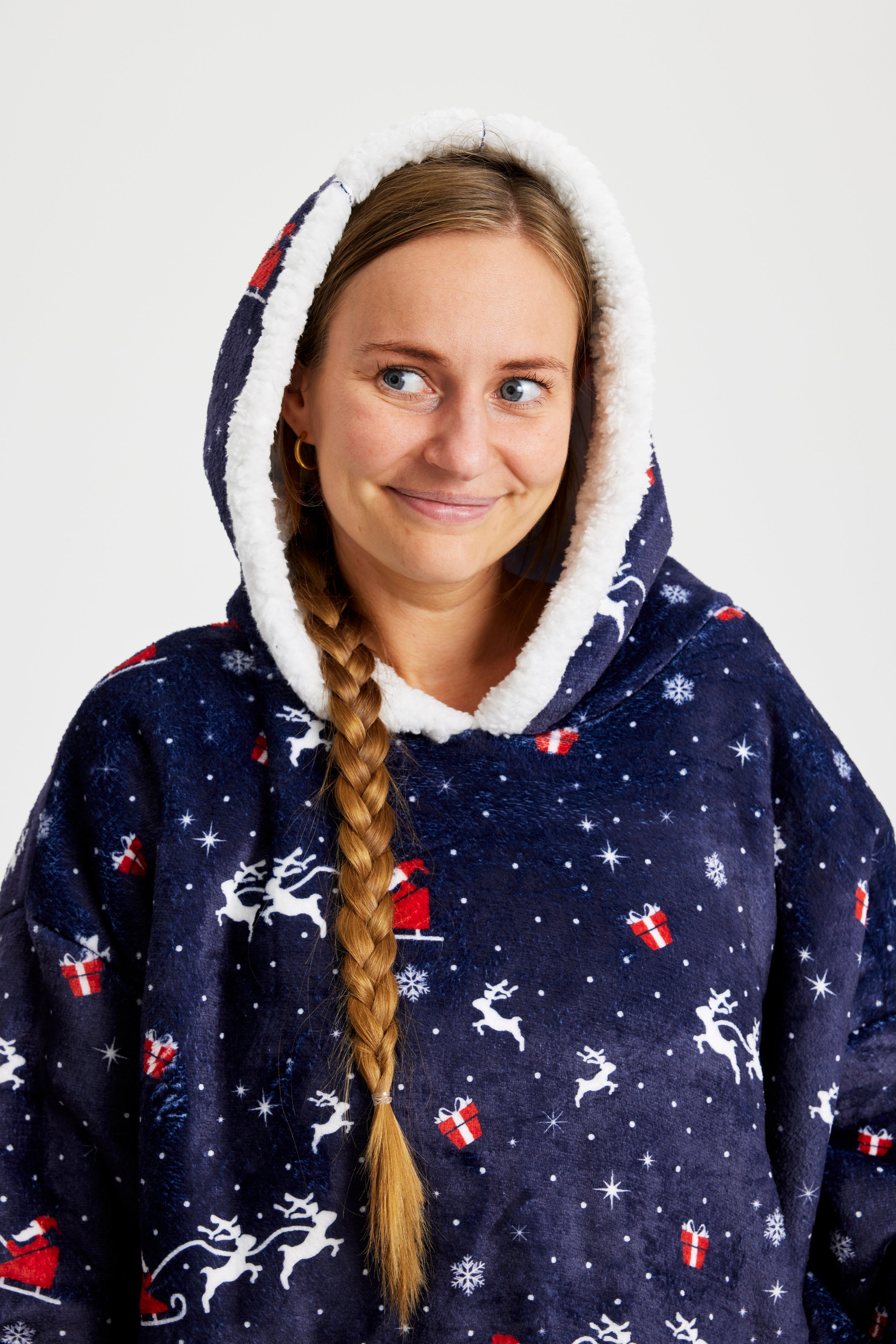 Een vrouw die opzij kijkt en een blauwe kerst hoodie met kerstprint draagt.