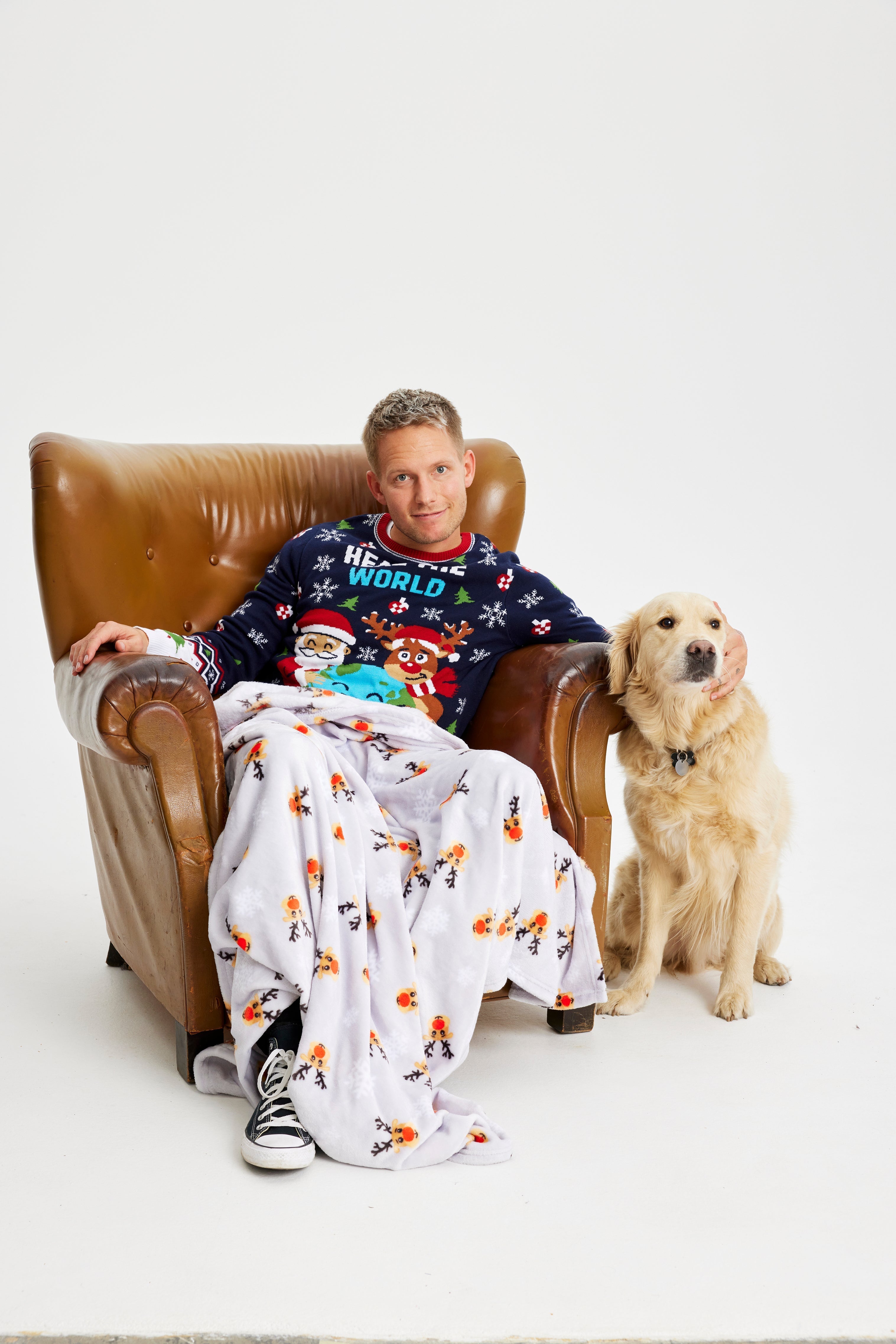 Een man in een stoel met een hond met een kerstdeken.