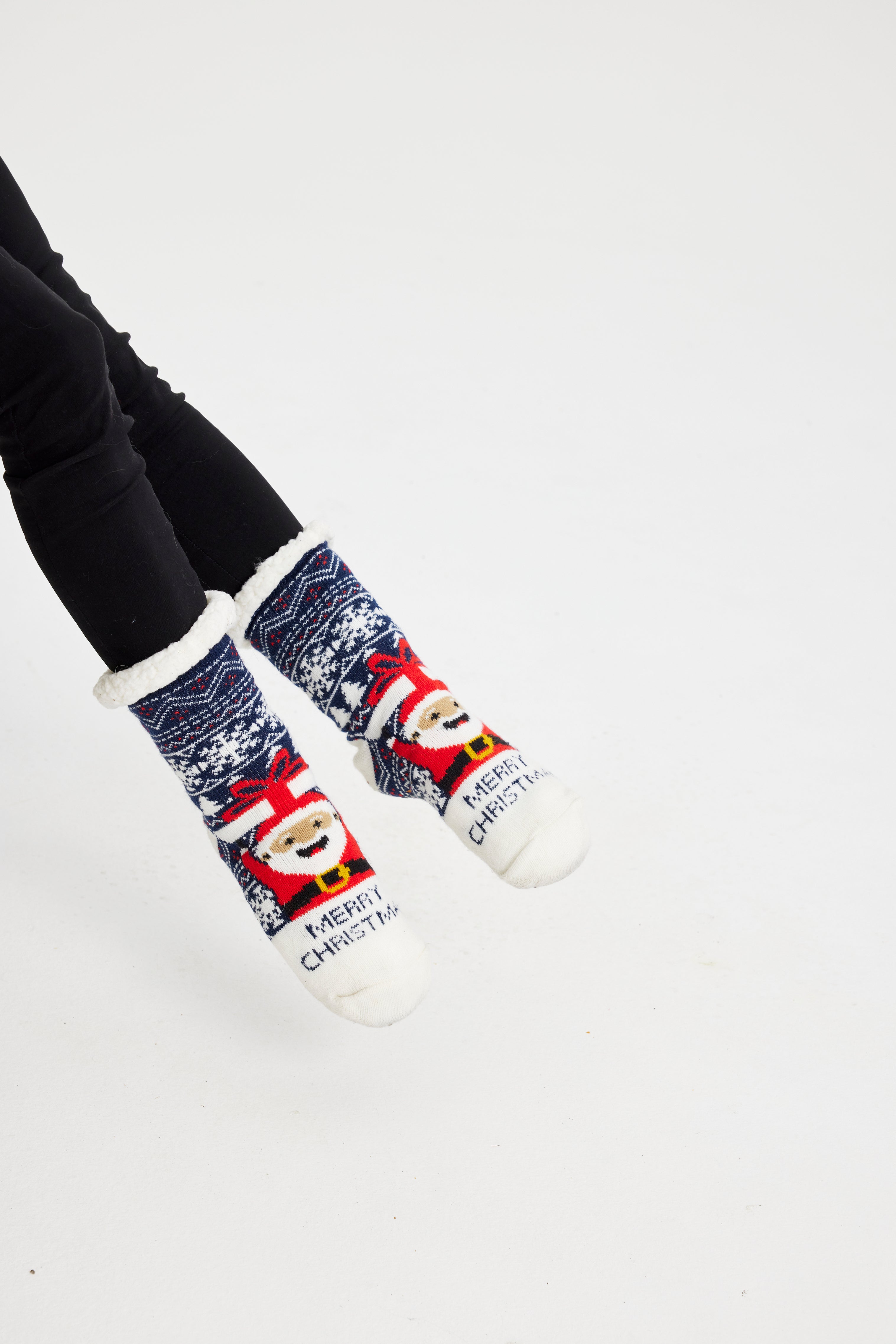 Een paar benen met blauwe kerstsokken met de kerstman erop.