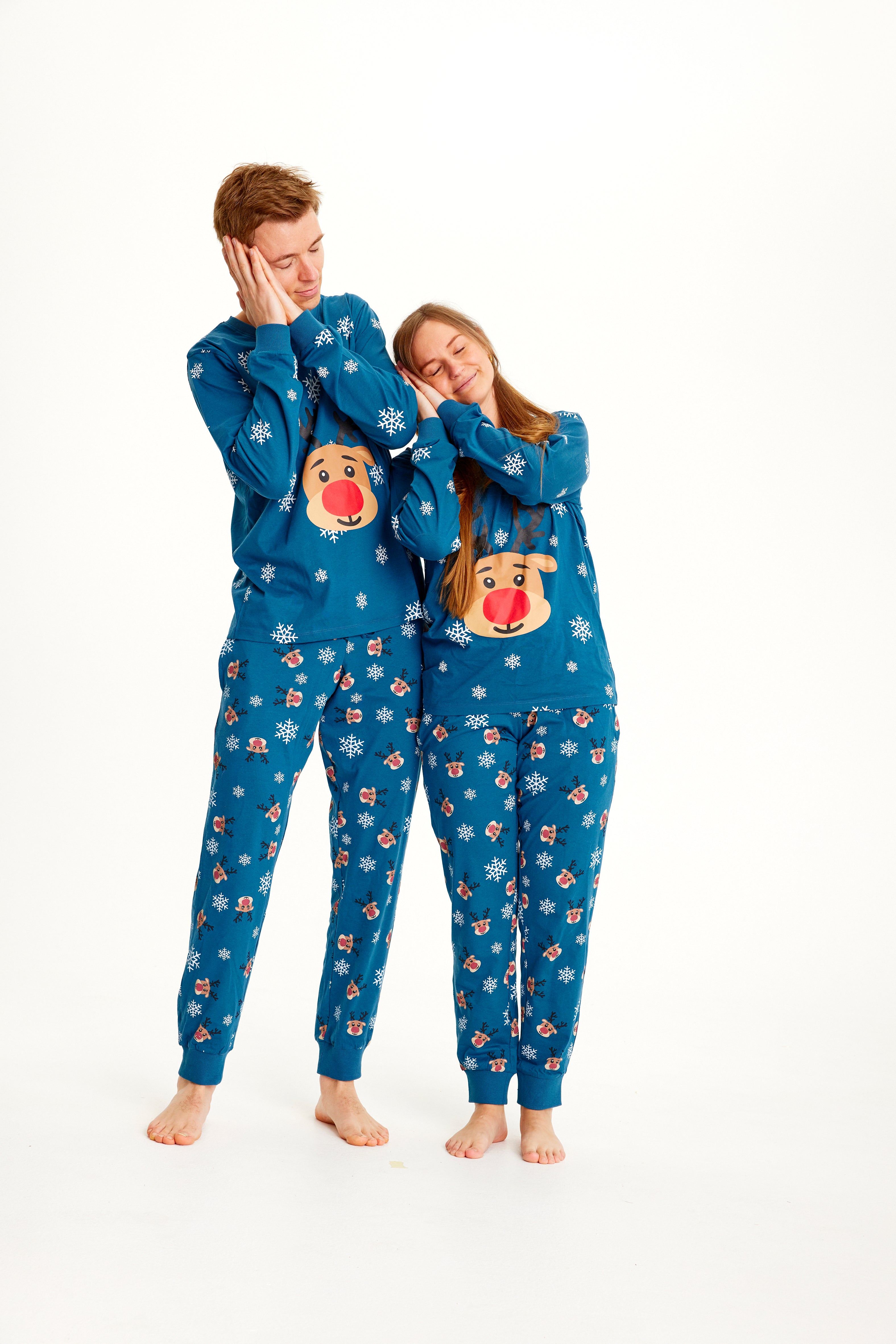 Een slapend stel in een blauwe kerstpyjama met Rudolph erop.