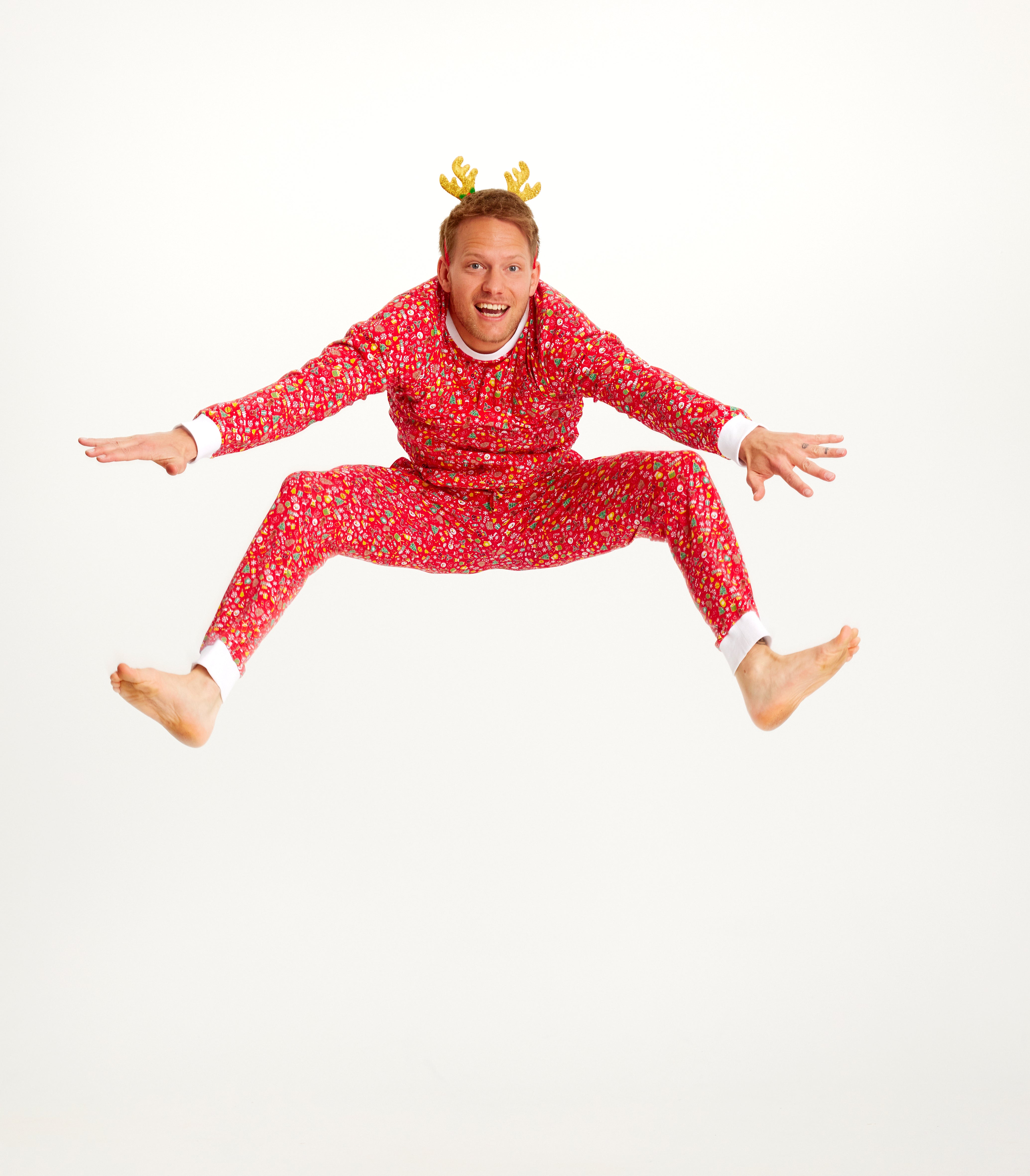Een springende man in een rode kerstpyjama.