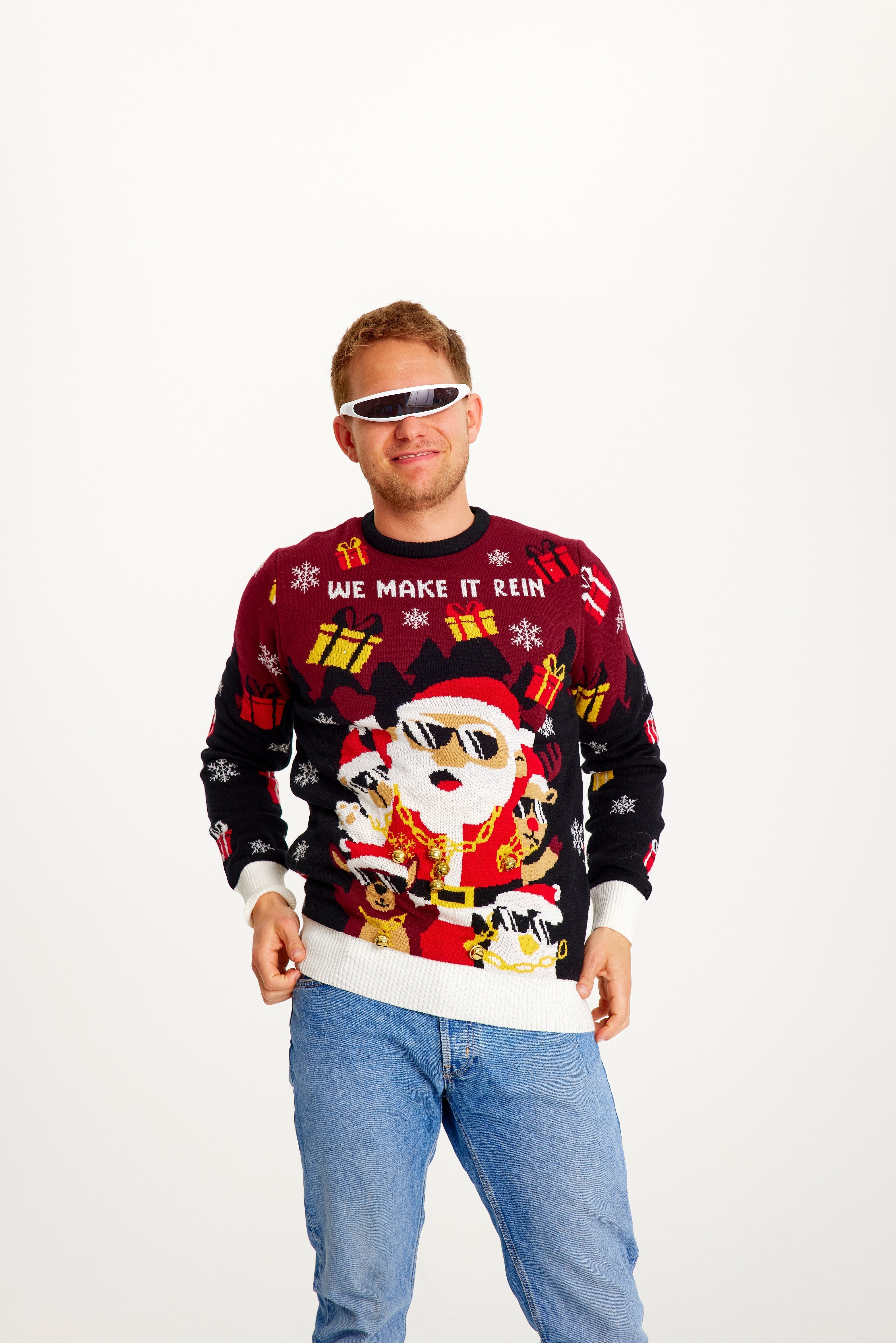 Een lachende man die een rode en zwarte kersttrui draagt met een kerstfiguurtje en cadeautjes.