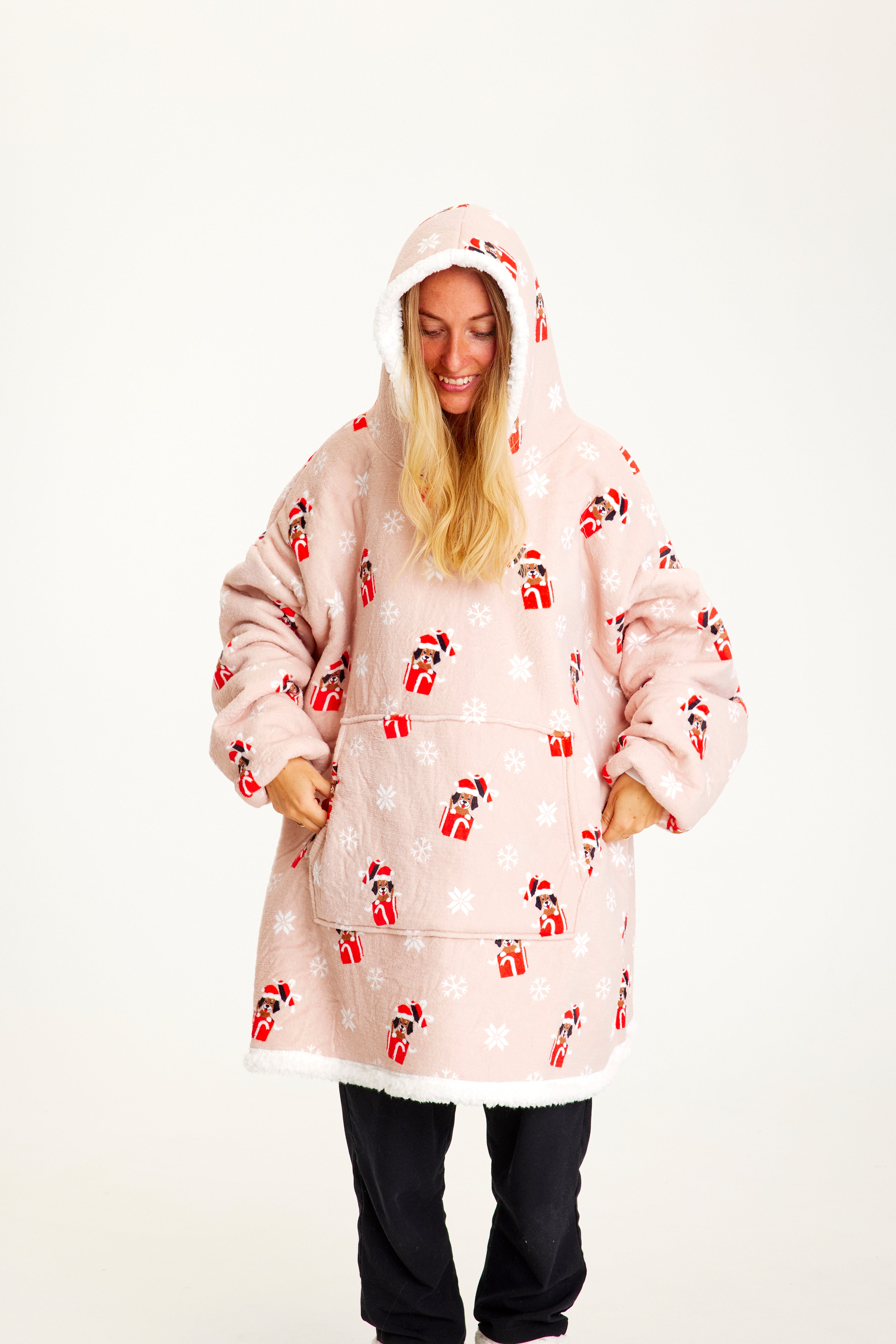 Een vrouw draagt een roze kerst hoodie met honden erop.