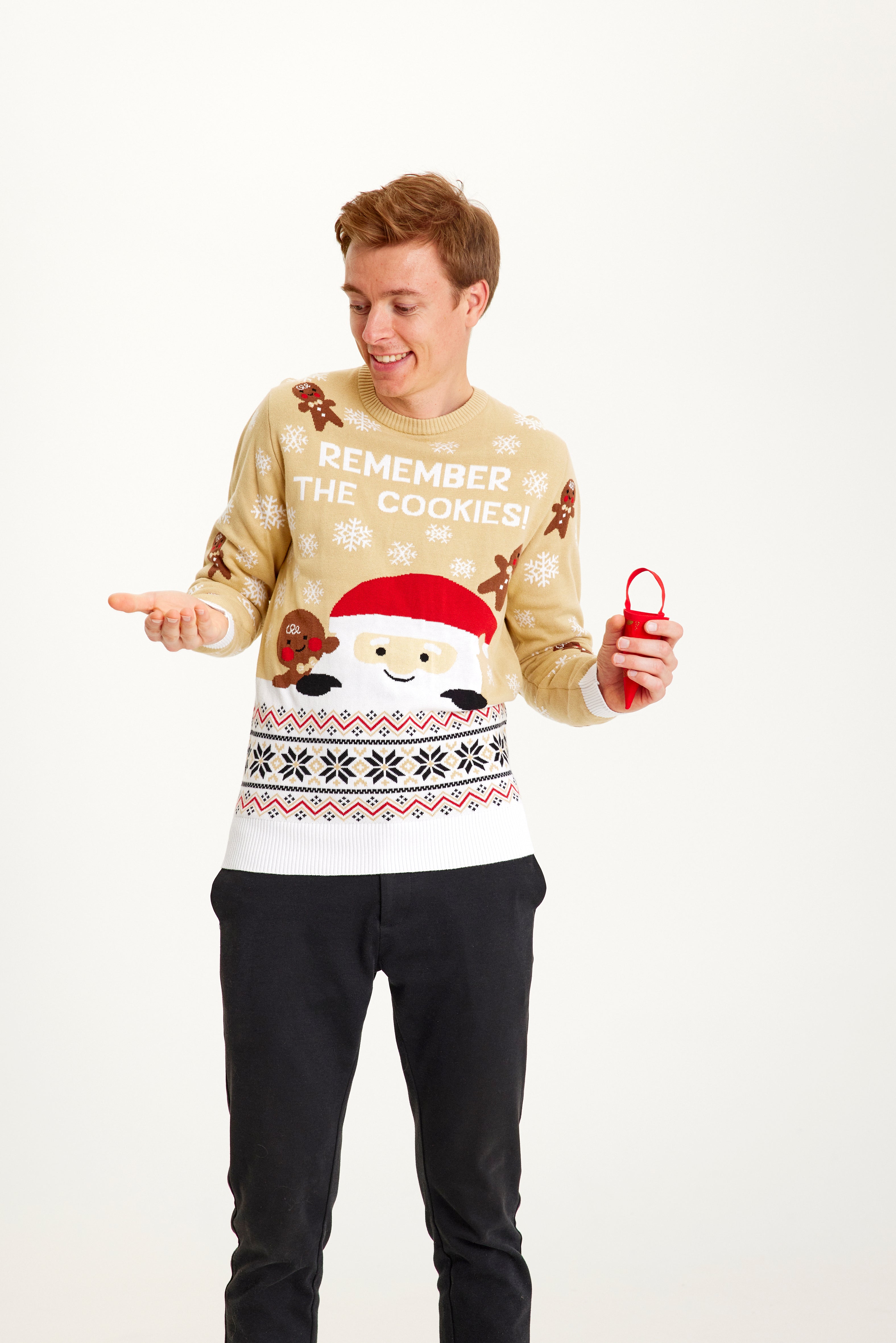 Een man poseert terwijl hij een beige kersttrui draagt met de quote 